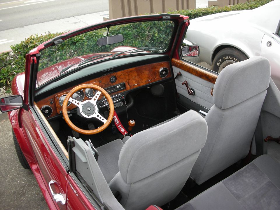 Interior of a red classic Mini convertible with wood dash and wood steering wheel
