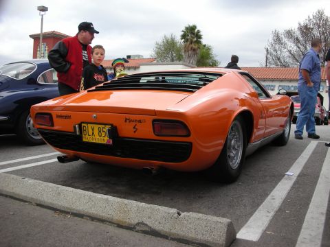 1998 Ford Crown Victoria - Rear view of an orange Lamborghini Miura S badged on the deck, Oregon plate BLX 851, with a man and children admiring it.