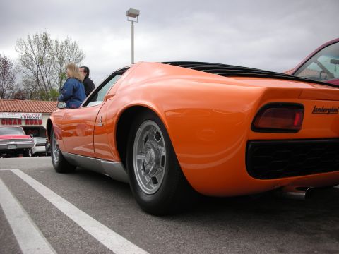 1998 Ford Crown Victoria - Low rear-quarter shot of an orange Lamborghini-badged Miura showing its five-spoke wheel, slatted engine deck and quad taillights.