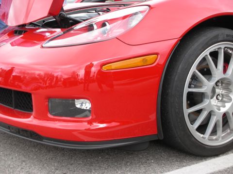 1998 Ford Crown Victoria - Close-up of a red Corvette's front fender, headlight and amber marker with a multi-spoke wheel and red brake caliper.
