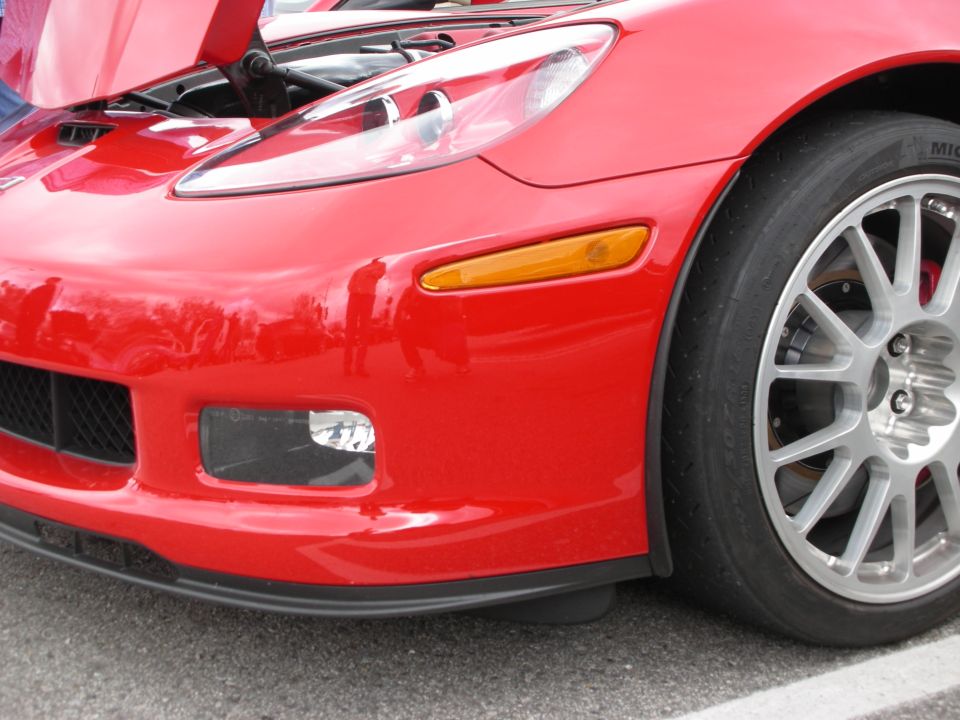Front corner close-up of a red Chevrolet Corvette with mesh wheel