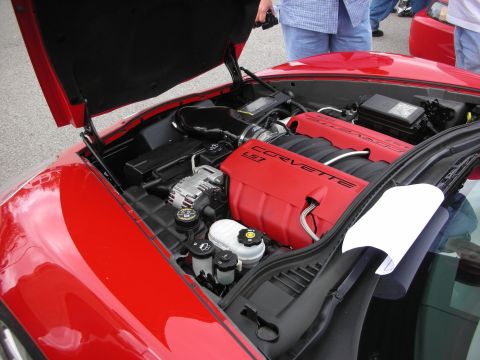 1998 Ford Crown Victoria - Engine bay of a red Corvette showing the V8 with a red Corvette LS intake cover under a raised hood.