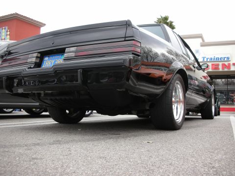 1998 Ford Crown Victoria - Low rear-quarter shot of a black Buick Grand National-style coupe on polished wheels, California plate reading 1RRY 300.