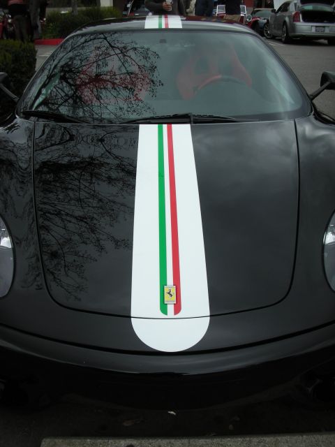 1998 Ford Crown Victoria - Close-up of a matte black Ferrari's hood and windshield showing a white racing stripe with green-white-red Italian colors and the prancing…