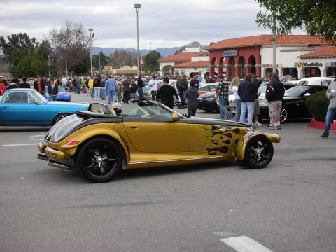 1998 Ford Crown Victoria - gold open-top roadster with black flame paint and chrome wheels sits in a parking lot crowded with spectators and other cars.