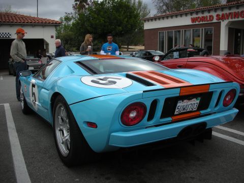 1998 Ford Crown Victoria - light blue Ford GT with orange Gulf stripes and a number 5 roundel parked at a car show outside a World Savings building.