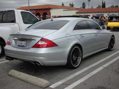 1998 Ford Crown Victoria - silver Mercedes CLS AMG four-door coupe with dark multi-spoke wheels parked in a lot near shops and a yellow car.