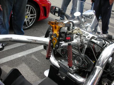1998 Ford Crown Victoria - Detail of a custom chopper showing chrome handlebars, red leather grips and exposed engine, with a red Ferrari behind.