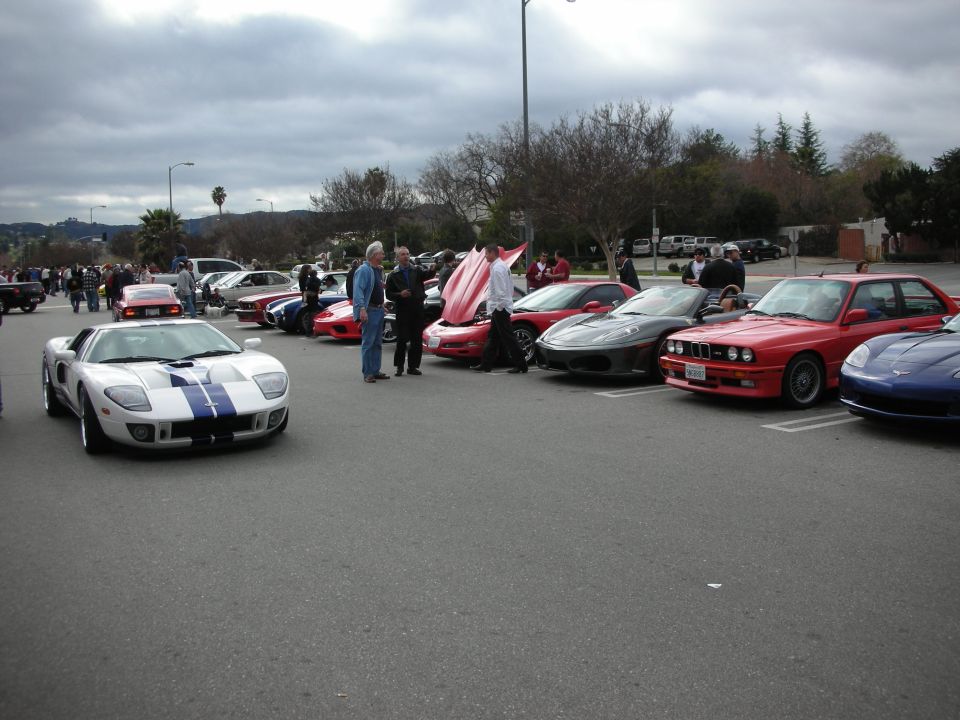 Row of sports cars including silver Ford GT and red BMW M3 at a lot meet