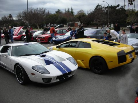 1998 Ford Crown Victoria - silver-and-blue Ford GT parked next to a yellow Lamborghini Murcielago among onlookers at a car meet.