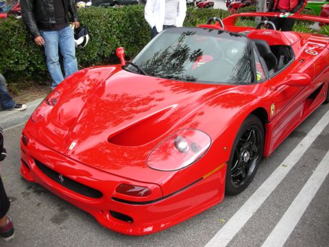 1998 Ford Crown Victoria - red Ferrari F50 open-top supercar with black wheels parked at the curb during an outdoor car gathering.