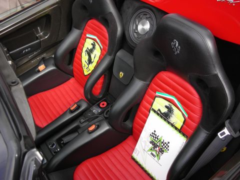 1998 Ford Crown Victoria - Interior of a Ferrari showing red-and-black sport seats embroidered with the prancing horse logo and an F50 sill plate.