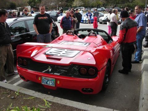 1998 Ford Crown Victoria - Rear three-quarter view of a red Ferrari F50 with louvered engine cover, surrounded by spectators at a meet.