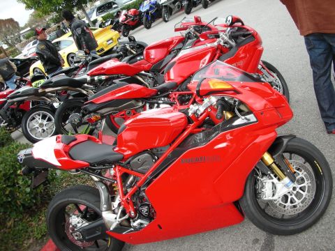 1998 Ford Crown Victoria - row of red Ducati sportbikes with gold forks and single-sided swingarms lined up at an outdoor bike meet.