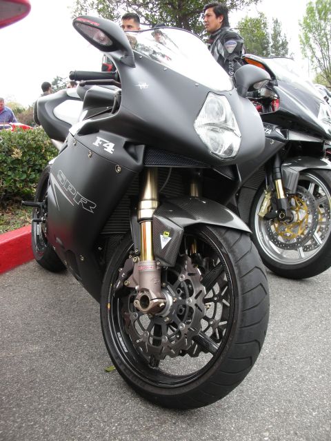 1998 Ford Crown Victoria - matte-black MV Agusta F4 SPR sportbike with gold upside-down forks and drilled brake discs, parked at a meet.