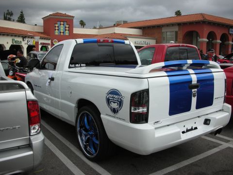 1998 Ford Crown Victoria - Rear view of a white Dodge Ram pickup with twin blue racing stripes, Viper badging, and chrome wheels in a lot.