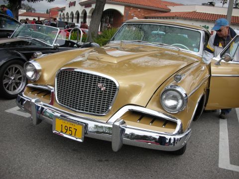 1998 Ford Crown Victoria - Front view of a gold 1957 Studebaker with chrome grille and a yellow California plate reading 1957 at a car show.