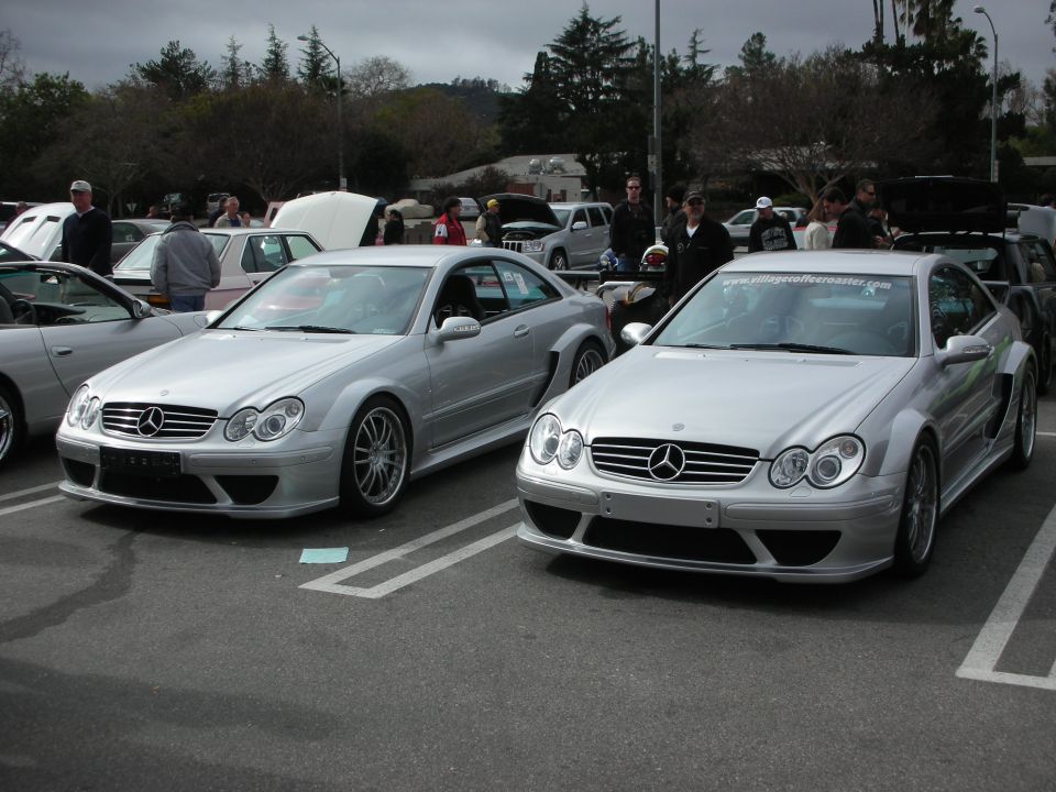 Two silver Mercedes-Benz CLK AMG coupes parked side by side at a car show