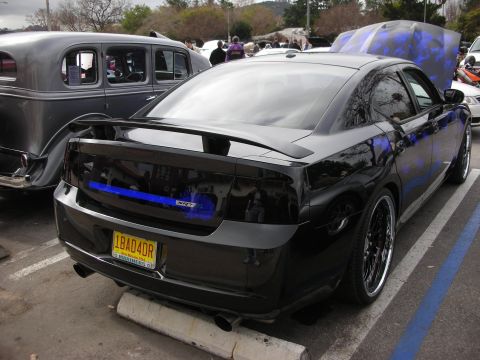 1998 Ford Crown Victoria - Rear three-quarter view of a black Dodge Charger SRT with a vanity plate reading IBAD4DR parked at a car show.