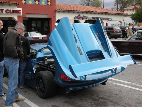 1998 Ford Crown Victoria - blue custom sports car with its full rear clamshell bodywork raised draws onlookers in a strip-mall lot.