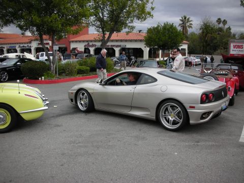 1998 Ford Crown Victoria - Rear three-quarter view of a silver Ferrari 360 coupe parked in a lot beside a yellow classic at a car show.