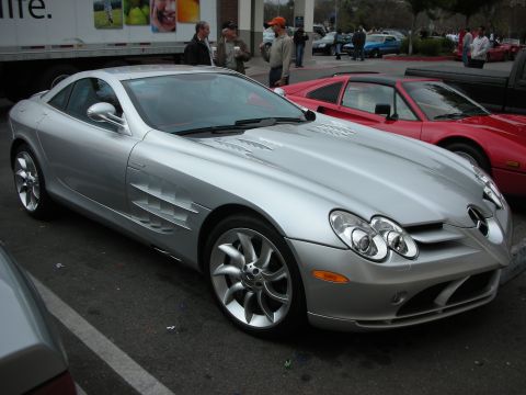1998 Ford Crown Victoria - silver Mercedes-Benz SLR McLaren coupe with side exhaust vents parked beside red cars at an outdoor show.