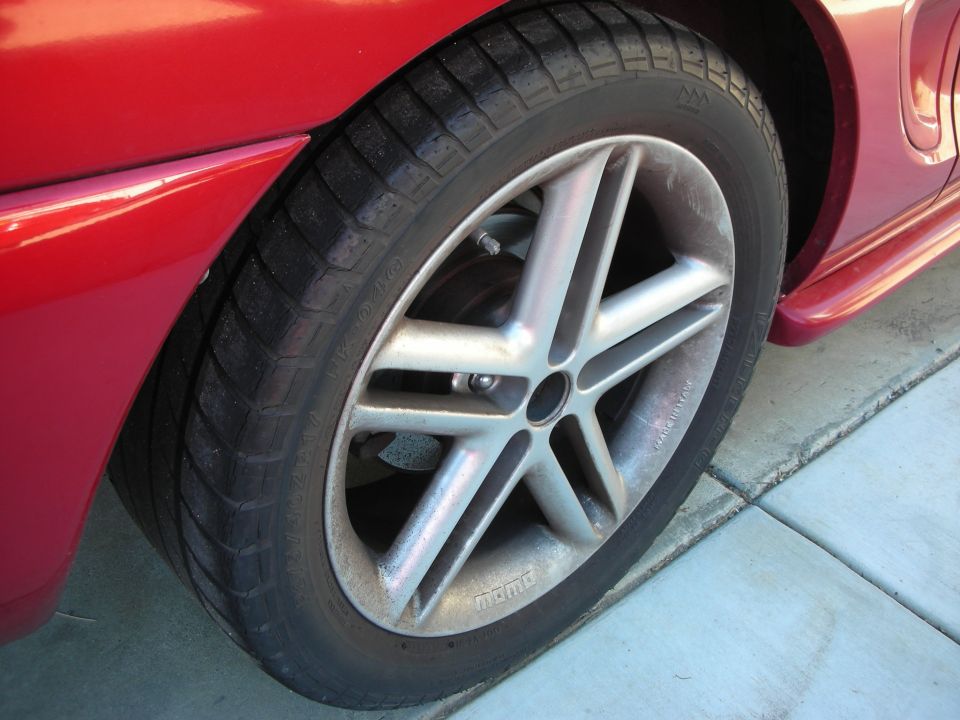 Close-up of a red car's silver five-spoke wheel and tire with Nemo branding