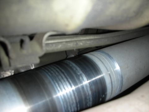 1998 Ford Crown Victoria - close-up underbody view shows a polished metal driveshaft and surrounding chassis components beneath a vehicle.
