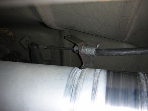 1998 Ford Crown Victoria - underbody view shows a parking-brake cable and lever bracket near a polished metal driveshaft on a vehicle's floorpan.