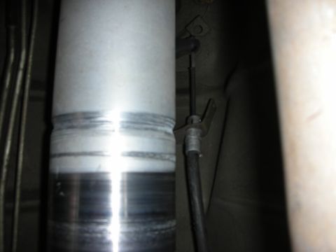 1998 Ford Crown Victoria - close-up underbody shot of a polished aluminum driveshaft alongside a brake cable and mounting bracket.