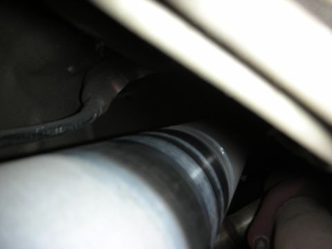 1998 Ford Crown Victoria - underbody view shows a polished metal driveshaft and exhaust piping among the chassis components of a vehicle.
