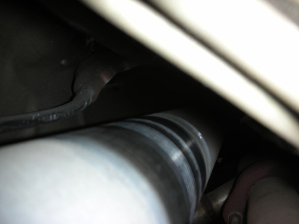 Underbody view of a polished driveshaft and exhaust components beneath a vehicle