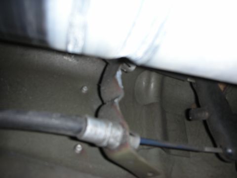 1998 Ford Crown Victoria - underbody view of a vehicle floorpan showing a mounting bracket, brake cable and a polished metal driveshaft.