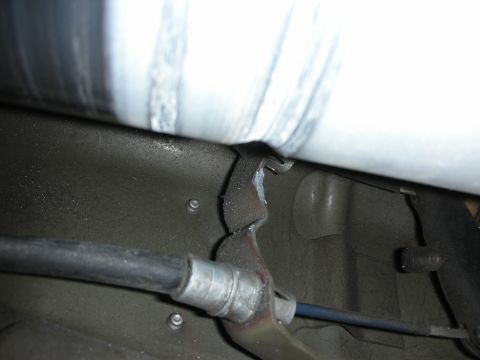 1998 Ford Crown Victoria - underbody close-up shows a welded mounting bracket, routed brake cable and a metal driveshaft beneath a vehicle.