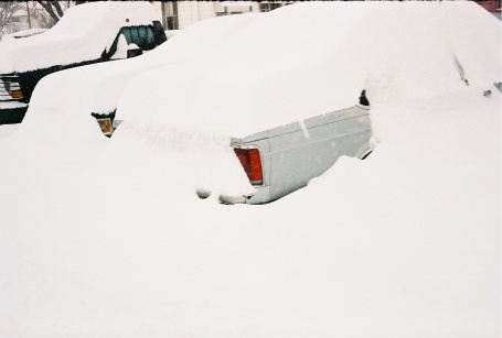 1989 Ford LTD Crown Victoria - A full-size sedan buried nearly to the roofline in deep snow, with only the rear quarter panel, taillight lens and a sliver of chrome trim…