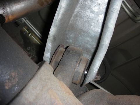 1998 Ford Crown Victoria - Detailed underside view of a metal transmission mount bracket and rubber isolator near exhaust piping.