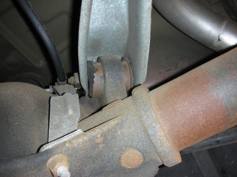 1998 Ford Crown Victoria - Underside close-up showing a surface-rusted driveshaft, a mounting bracket and bolted hardware.