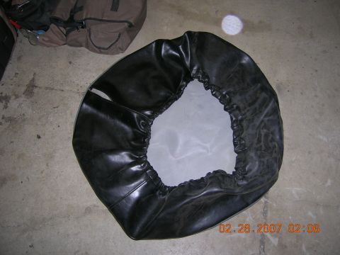 1996 Ford Bronco - Spare tire cover shown on a concrete floor with bags in the background.