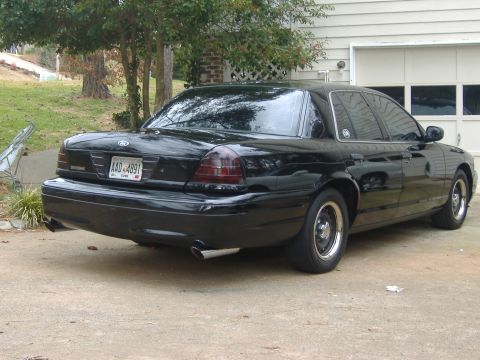2001 Ford Crown Victoria - This black sedan is parked in front of a garage. The license plate is visible.