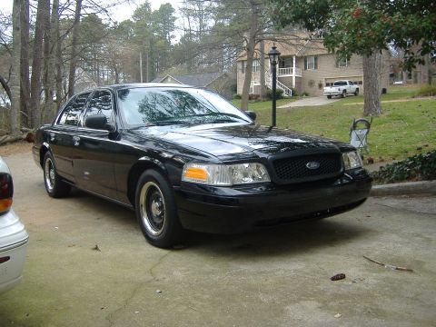2001 Ford Crown Victoria - A black 2001 Ford Crown Victoria sedan is parked in front of a house.