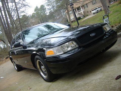 2001 Ford Crown Victoria - A black 2001 Ford Crown Victoria is parked on a concrete driveway in front of a house.