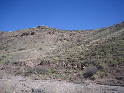 1996 Ford Bronco - A wide view of a dry, rocky hillside with minimal vegetation under a bright blue sky.