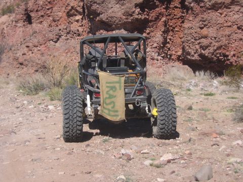 1996 Ford Bronco - A modified off-road vehicle is parked on a dirt path with a rocky hillside in the background.