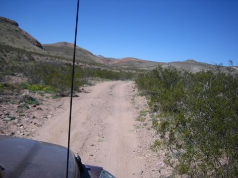 1996 Ford Bronco - Driving on a dusty track through a barren landscape under a clear blue sky.