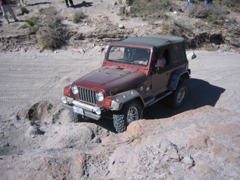 1996 Ford Bronco - Jeep Wrangler TJ tackling an off-road trail with rocky obstacles.