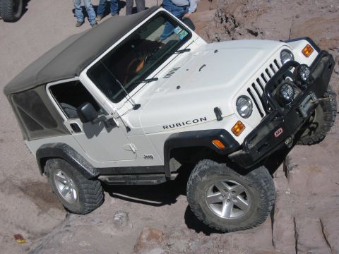1996 Ford Bronco - A white Jeep Wrangler Rubicon navigates a challenging rocky trail.