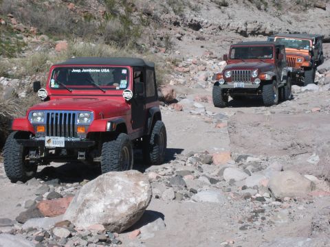 1996 Ford Bronco - Multiple Jeeps drive on a rocky, off-road path.