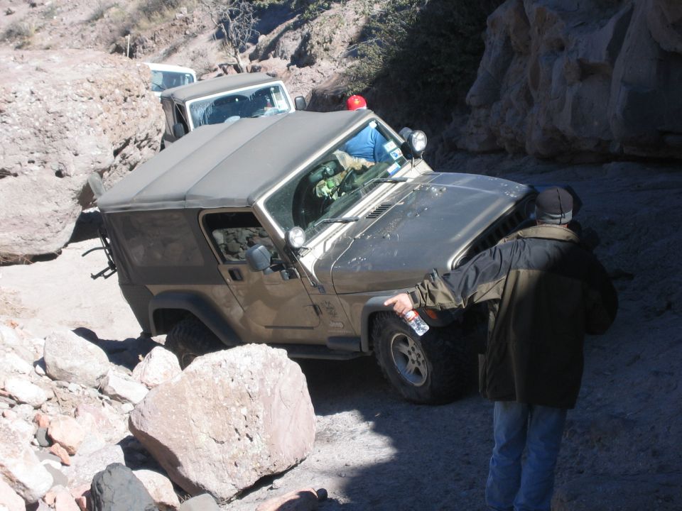 Two Jeep Wranglers navigating a rocky off-road trail, one is gold and the other is white
