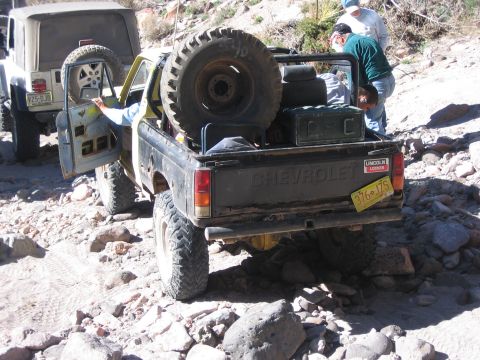 1996 Ford Bronco - Two off-road vehicles navigate a rocky trail, with a Chevrolet pickup truck loaded with a spare tire.