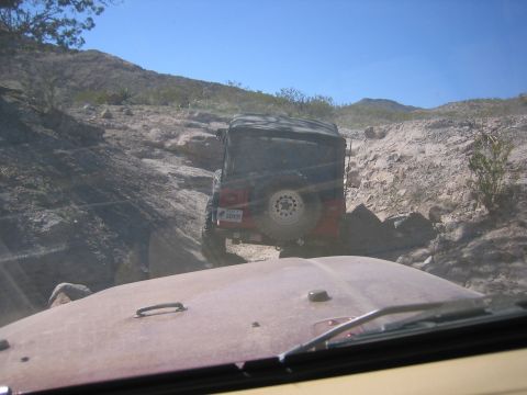 1996 Ford Bronco - Two Jeeps navigate a challenging rocky trail under a clear blue sky.